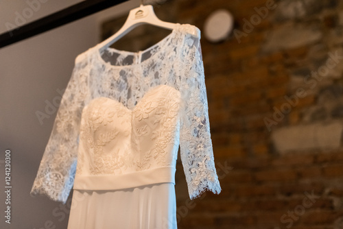 Elegant wedding dress showcased in a rustic setting with exposed brick walls and soft natural lighting