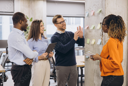 Collaborative team brainstorming project strategy, using multicolored sticky notes in modern bright office environment