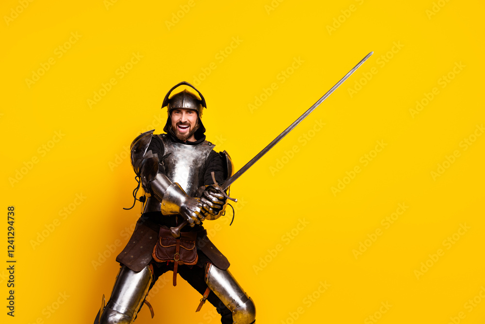 Young man in medieval knight armor holding sword on vibrant yellow background Young man in medieval knight armor holding sword on vibrant yellow background