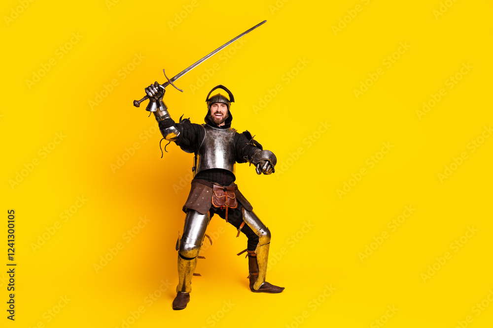 Young armored man in medieval costume poses with sword on vibrant yellow background Young armored man in medieval costume poses with sword on vibrant yellow background