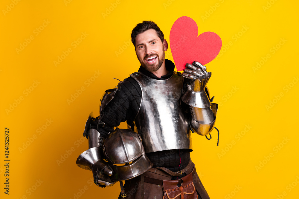 Naklejka premium Man in medieval knight armor holding a heart prop on bright yellow background
