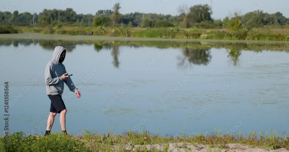 Caucasian Man Walks With Smartphone Near River. Hiking on Nature. Slow motion 60fps 4K 10-bit Caucasian Man Walks With Smartphone Near River. Hiking on Nature. Slow motion 60fps 4K 10-bit