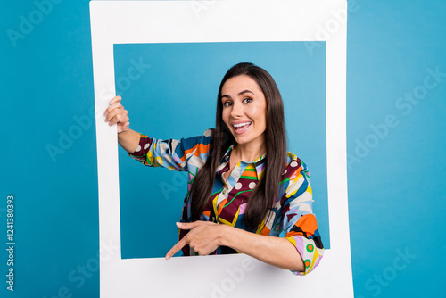 Portrait of girlish girl with straight hair dressed print blouse posing in frame indicating empty space isolated on blue color background