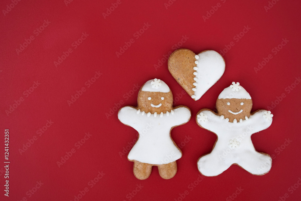 Fototapeta premium Smiling gingerbread woman, man and heart, red background, copy space for text