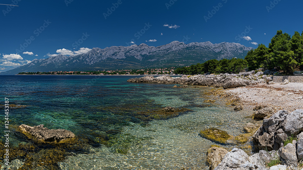 Coastal scene: crystal-clear water, rocky shore, and majestic mountains under a blue sky. Coastal scene: crystal-clear water, rocky shore, and majestic mountains under a blue sky.