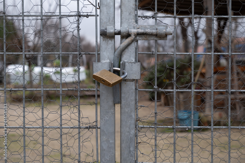 Lock securing metal fence, blurred garden in the background Lock securing metal fence, blurred garden in the background