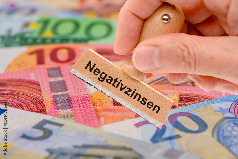 Über vielen Euroscheinen wird ein Holzstempel gehalten mit der Aufschrift Negativzinsen - FOTOMONTAGE