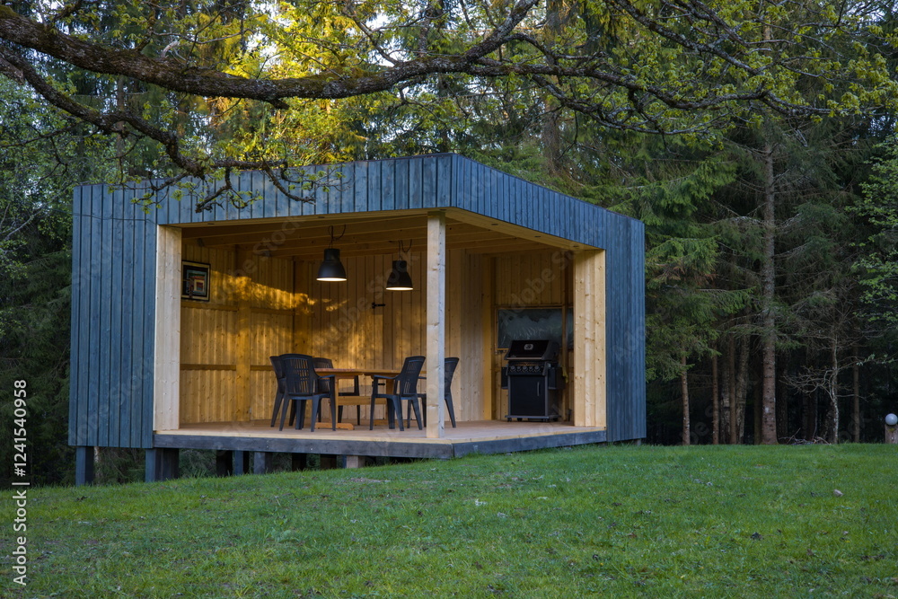 Modern wooden gazebo in a serene forest setting. Contemporary cube design with table and chairs.