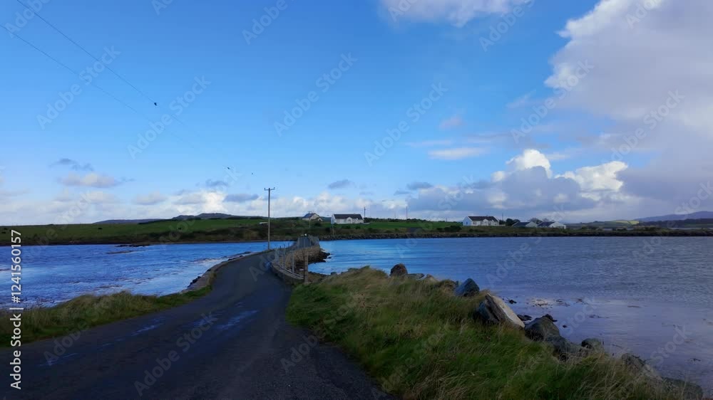Island Roy in Donegal A stunning and picturesque coastal road that gracefully winds through serene waters beneath a bright blue sky Island Roy in Donegal A stunning and picturesque coastal road that gracefully winds through serene waters beneath a bright blue sky