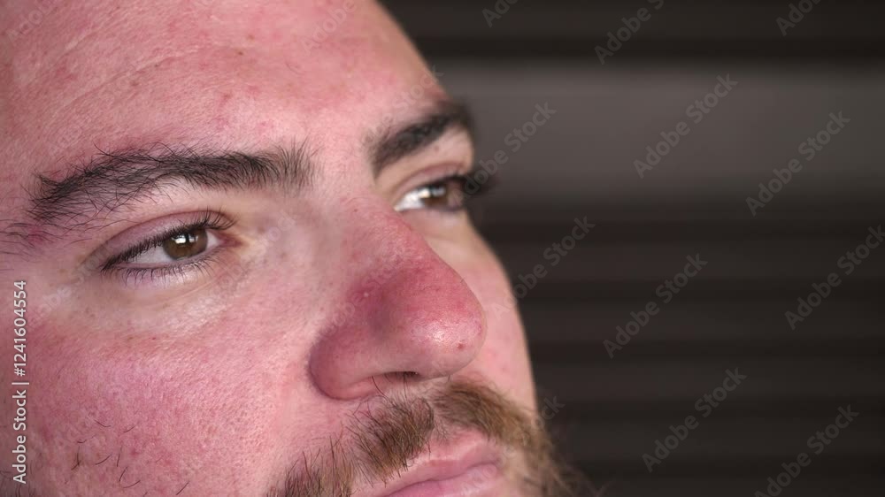 A side view captures a young man with a serious expression, revealing a hint of sadness as he reflects on his thoughts. A side view captures a young man with a serious expression, revealing a hint of sadness as he reflects on his thoughts.