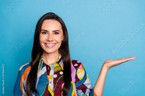 Photo portrait of attractive young woman hold empty space dressed stylish colorful print clothes isolated on blue color background