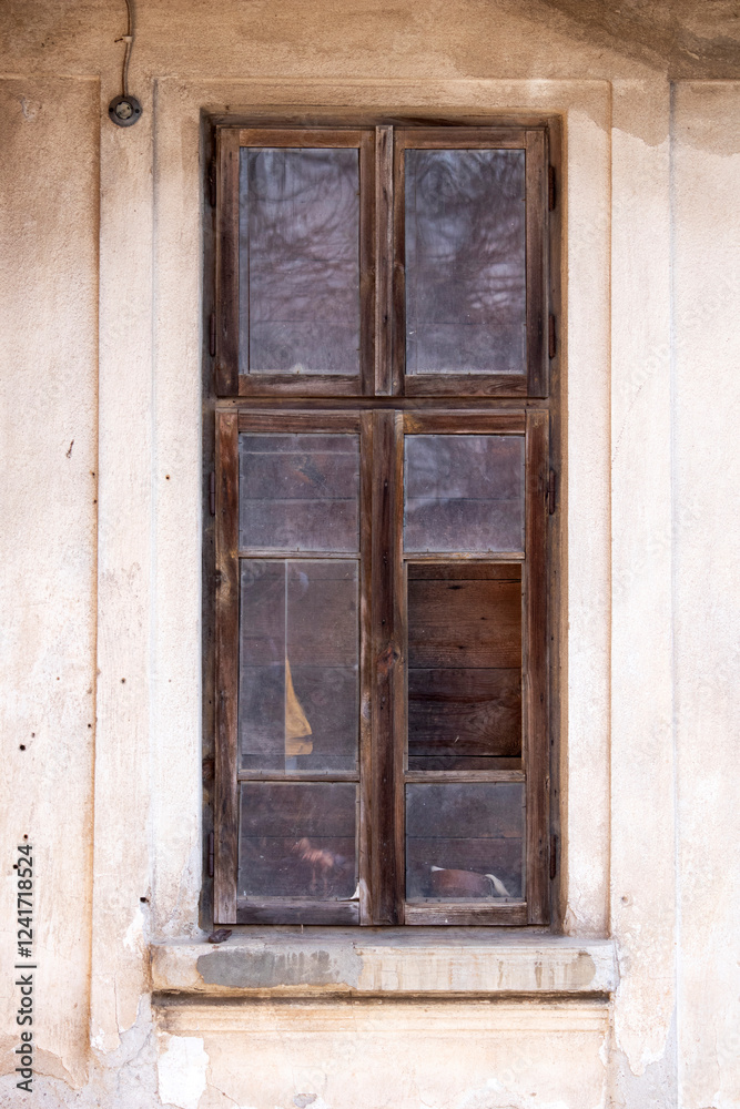 Old wooden window with broken glass on the wall of an abandoned house Old wooden window with broken glass on the wall of an abandoned house