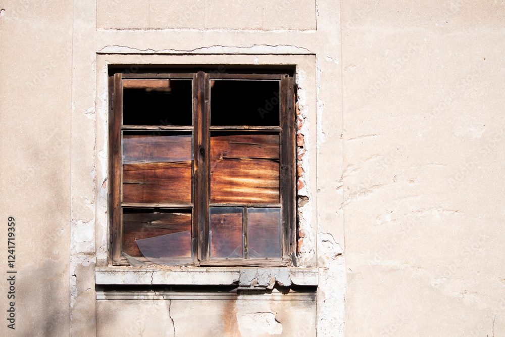 Obraz premium Old wooden window with broken glass on the wall of an abandoned house