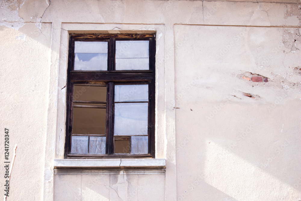Fototapeta premium Old wooden window with broken glass on the wall of an abandoned house