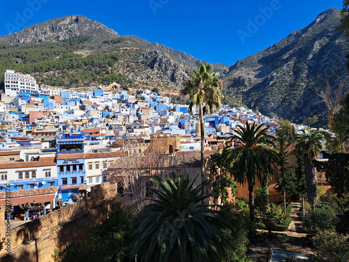 Vibrant Blue Buildings Nestle Among the Mountains in Chefchaouen's Enchanting Landscape on a Clear Sunny Day