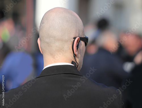 secret service bodyguard with earpiece monitoring the crowd