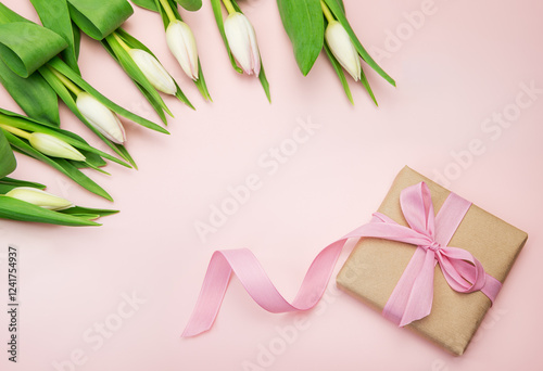 A bouquet of fresh cut pink tulips and a gift box with a ribbon on a pink background with a ribbon. Spring Festival.