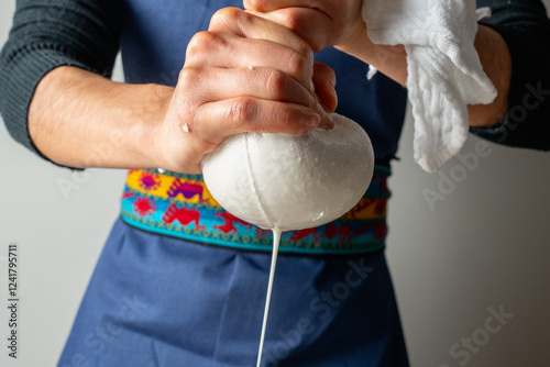 Chef squeezing almond milk through cloth strainer, preparing vegan milk photo