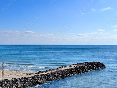 breakwater on the beach and clouds on a blue sky