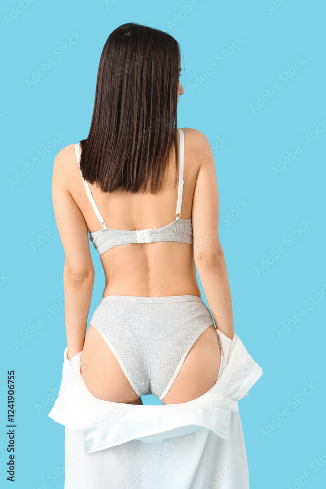 Obraz premium Slim young woman in underwear on blue background, back view