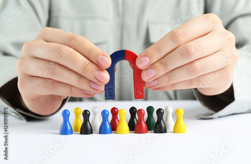 Woman with magnet attracting game pieces at white table, closeup
