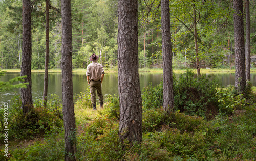 Man looking over a small lake in a forest