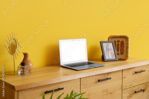 Bilde på lerret Blank laptop with frames on wooden commode near yellow wall