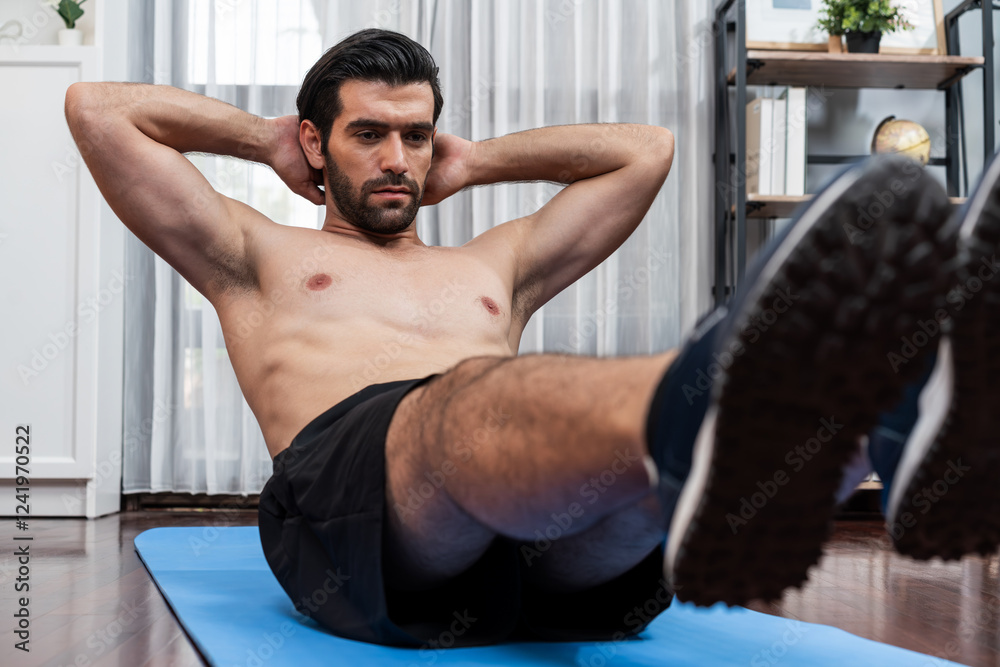 Obraz premium Athletic and sporty man doing crunch on fitness mat during home body workout exercise session for fit physique and healthy sport lifestyle at home. Gaiety home exercise workout training concept.