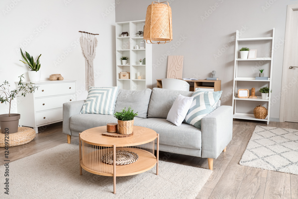 Obraz premium Interior of light living room with grey sofa, coffee table and shelf units