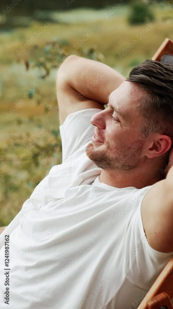 Caucasian man enjoying rest in the nature. Man sits comfortably in a folding chair, looking around. Vertical video Caucasian man enjoying rest in the nature. Man sits comfortably in a folding chair, looking around. Vertical video