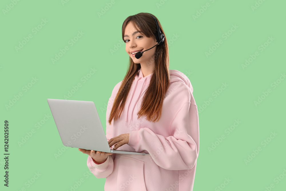 Teenage girl in headset with laptop working online on green background Teenage girl in headset with laptop working online on green background