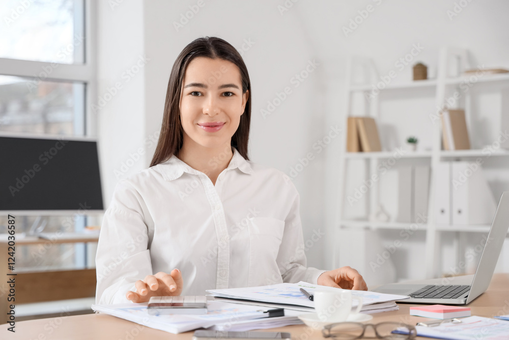 Young businesswoman with calculator working on report at table in office Young businesswoman with calculator working on report at table in office