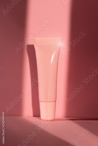 Mockup of a pink plastic tube for cream, lip gloss and other cosmetic grooming products on a pink background