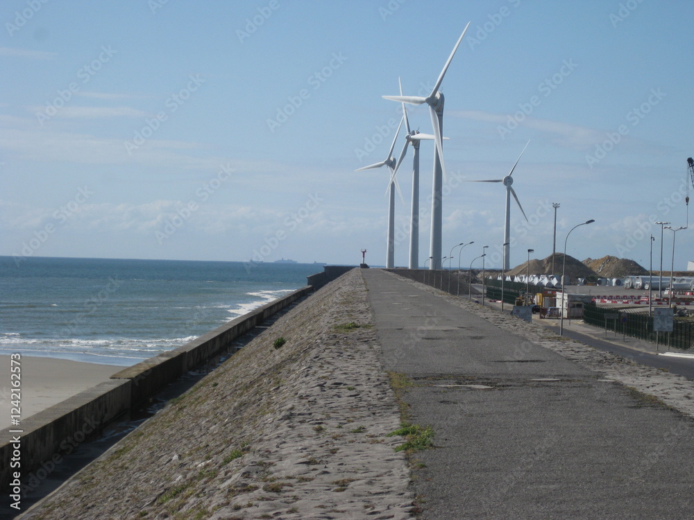 Wind turbine along a concrete jetty by the sea - Éolienne le long d'une jetée en béton au bord de la mer Wind turbine along a concrete jetty by the sea - Éolienne le long d'une jetée en béton au bord de la mer