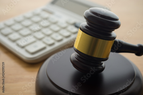 Gavel hammer judge and white calculator on wooden table background. Tax law, financial law or regulation, creative accounting, corruption, bribe, bankruptcy, penalty and so on concept.