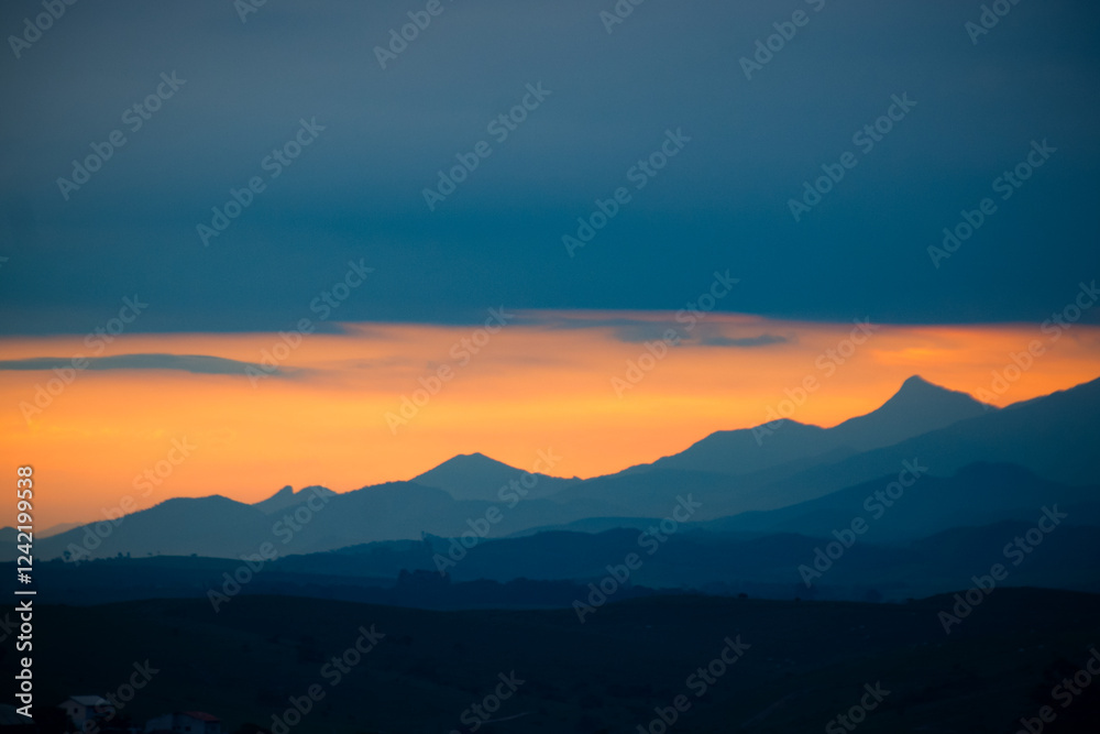 Silhouetted mountains at dusk under a dramatic orange sky Silhouetted mountains at dusk under a dramatic orange sky