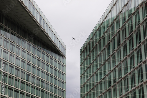 Airplane Flying Between Modern Glass Buildings photo