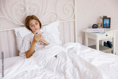 Teenage girl texting or messaging smartphone lying on bed at home photo