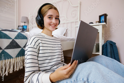 Portrait of girl looking at camera during doing homework on laptop photo