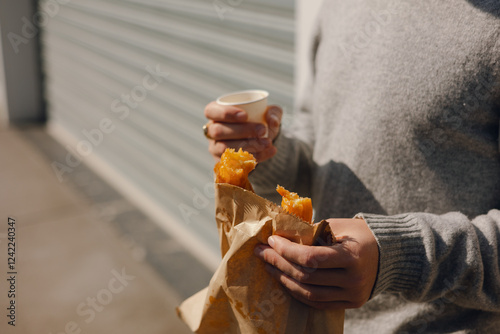 A male enjoying a pastry while holding a cop of coffee  photo