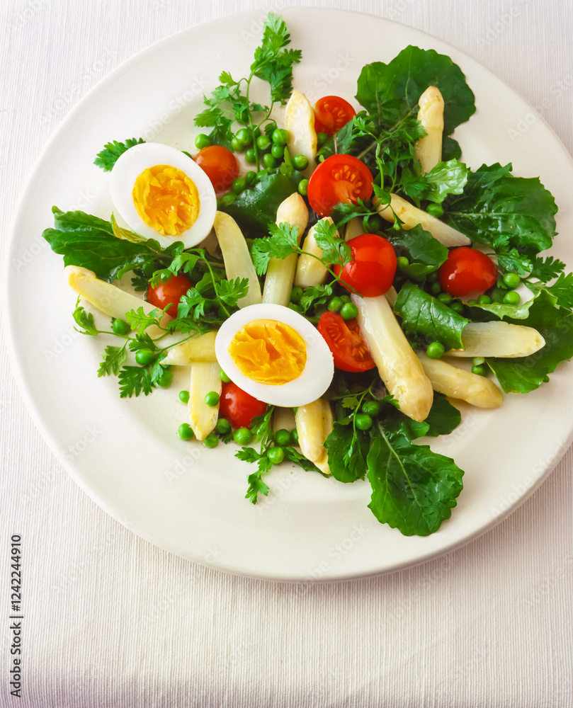 Fresh green salad with asparagus, cherry tomatoes, eggs and herbs