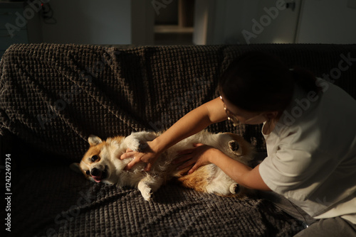 UGC side view shot of woman petting her corgi lying on sofa photo