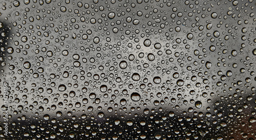 Close-up perpendicular shot of a water droplet-covered glass surface, with light refractions creating a unique texture