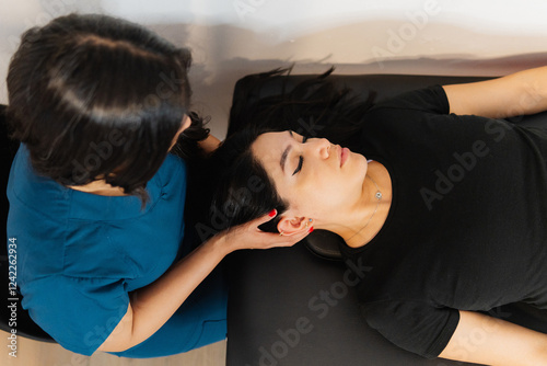 Relaxed patient lying down and receiving a neck massage.  photo