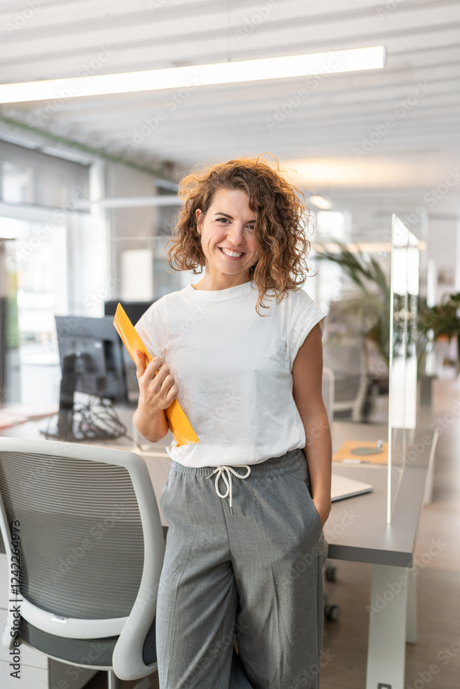 Young businesswoman smiling in modern coworking office holding folder Young businesswoman smiling in modern coworking office holding folder