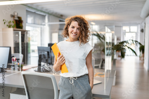 Young businesswoman smiling and holding a folder in a coworking