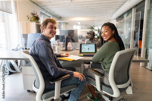 Coworkers smiling at coworking space using laptop photo