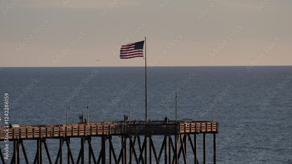 United States of America flag at end of pier at sunset blowing in the wind, slow motion - Ventura, California 
