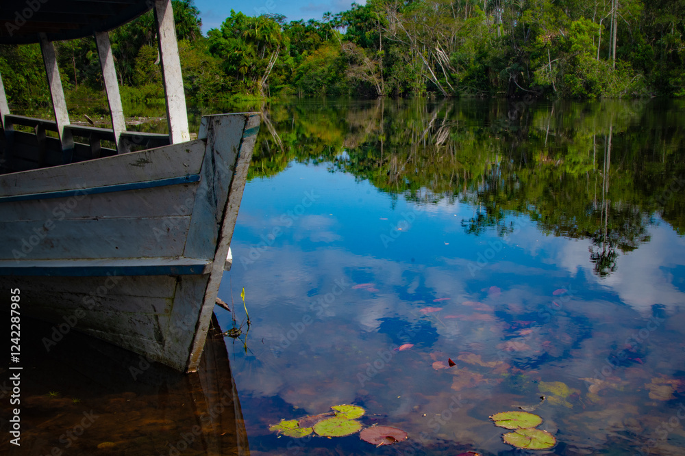 A wooden boat's bow rests on calm water, reflecting the sky and trees around the Rio Arapiuns. A wooden boat's bow rests on calm water, reflecting the sky and trees around the Rio Arapiuns.