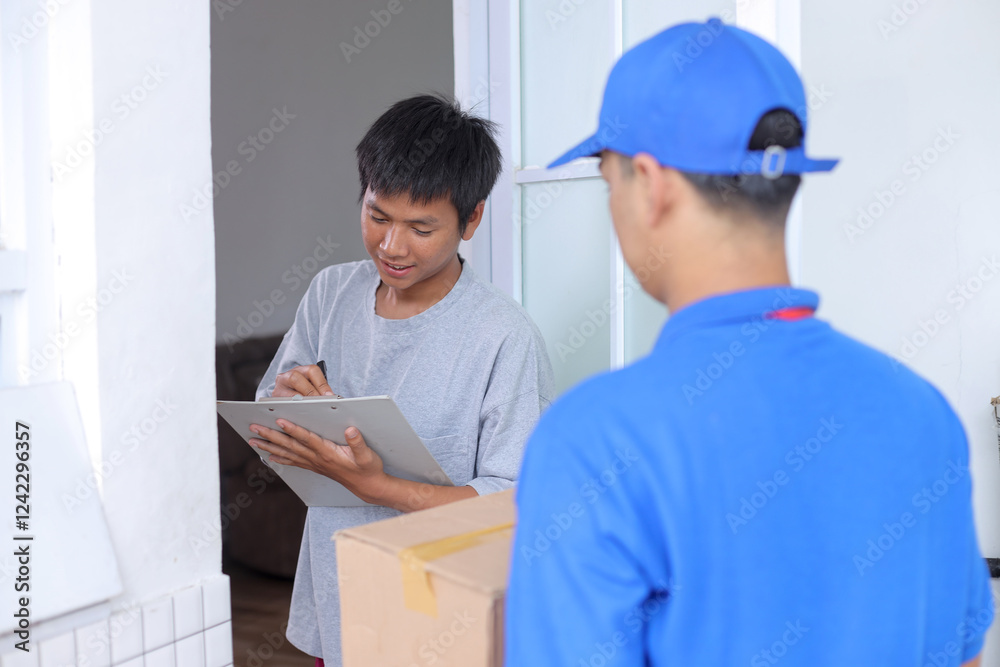 Delivery Man Holding Cardboard Box While Customer Hand Putting Signature on Clipboard